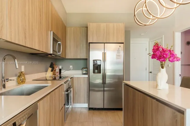 a kitchen with stainless steel appliances granite countertop a sink a refrigerator and a white cabinets