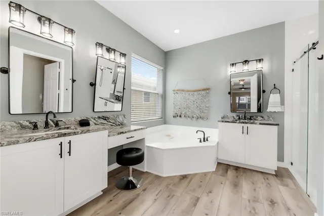 a bathroom with a bathtub double vanity sink and mirror