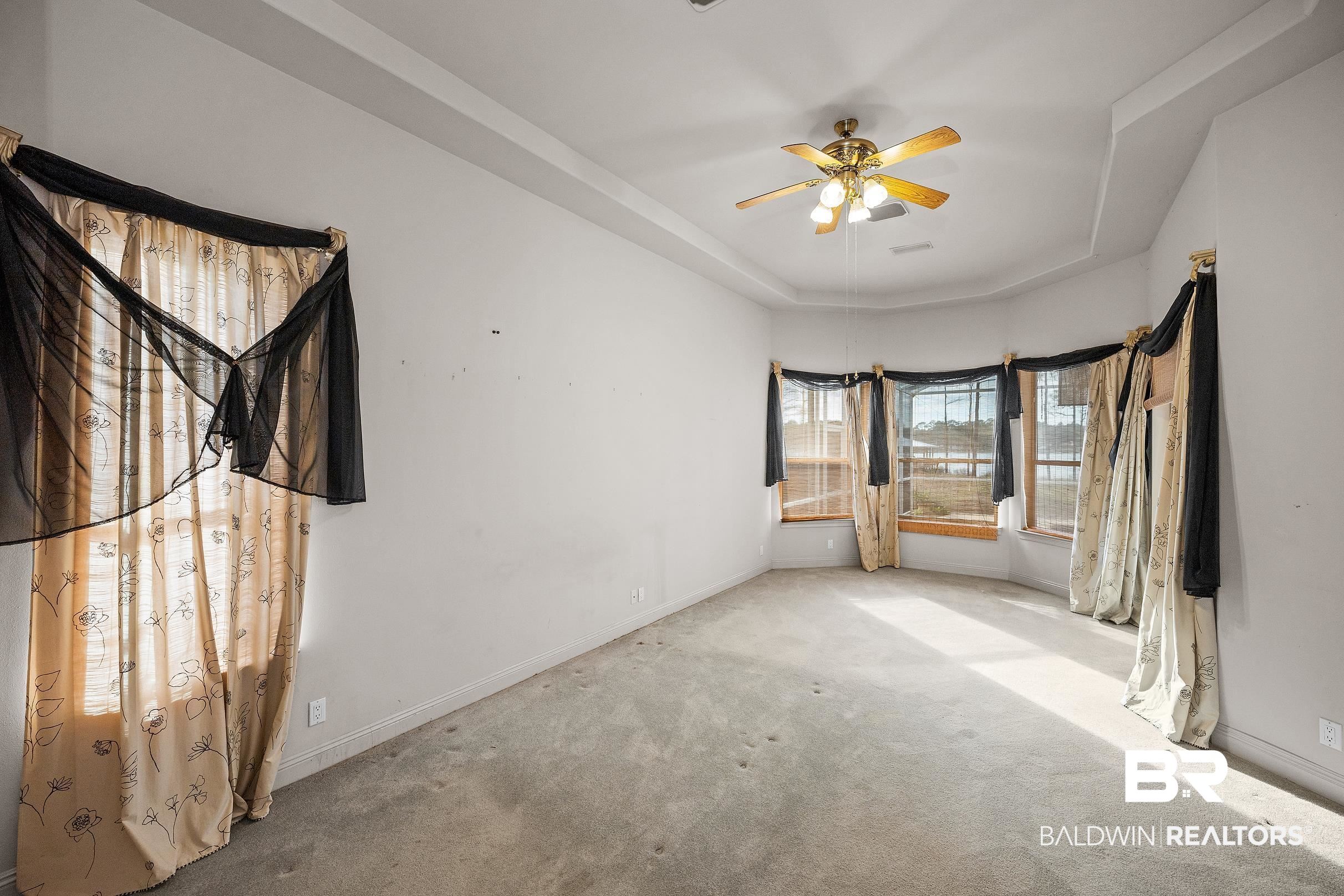 8591 Bay Harbor Road Elberta, AL 36530 - Photo 30 of 56 Unfurnished bedroom featuring a tray ceiling, ceiling fan, and carpet