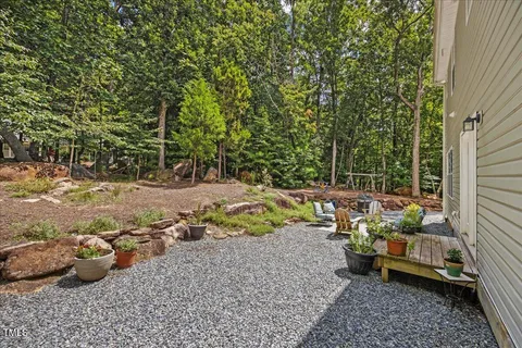 a view of a backyard with chairs and potted plants