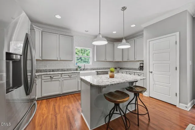 a kitchen with stainless steel appliances granite countertop a sink a stove a refrigerator and island with wooden floor