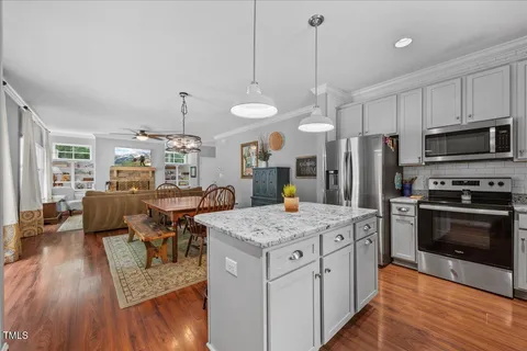 a open kitchen with stainless steel appliances granite countertop a stove and refrigerator a oven with wooden floors