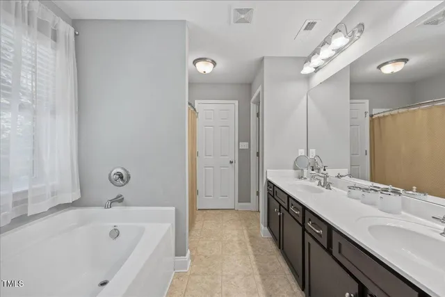 a spacious bathroom with a tub sink shower and mirror