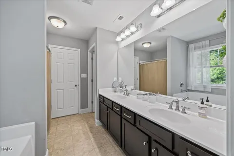 a spacious bathroom with a double vanity sink a mirror and a shower