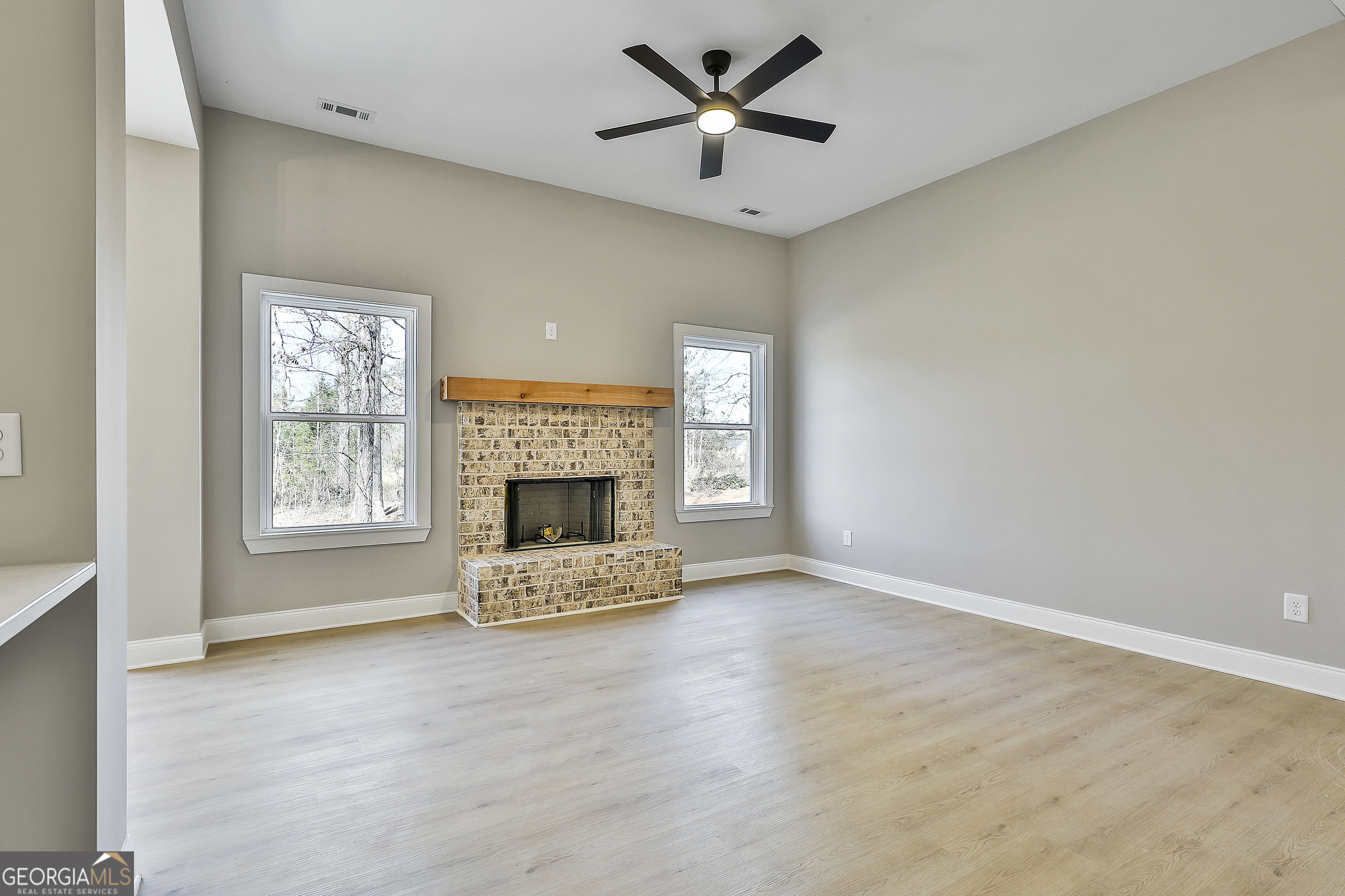 35 Oak Road Locust Grove, GA 30248 - Photo 9 of 36 a view of a livingroom with a fireplace a ceiling fan and windows