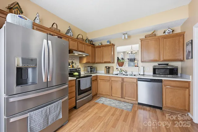 a kitchen with stainless steel appliances granite countertop a refrigerator a stove and a sink with cabinets
