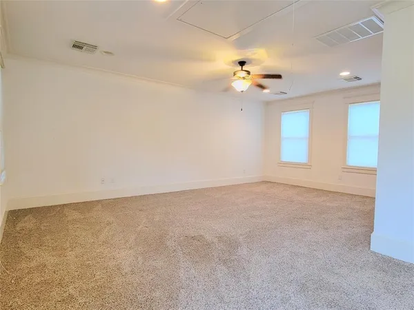 an empty room with chandelier fan and windows