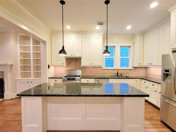 a kitchen with kitchen island granite countertop a sink a counter top space appliances and cabinets