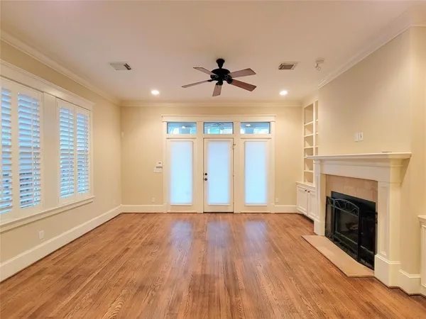 an empty room with wooden floor fireplace and windows
