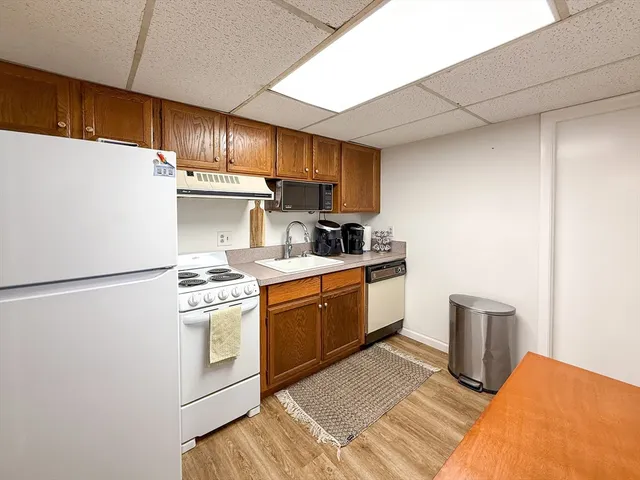 a kitchen with stainless steel appliances granite countertop a refrigerator sink a stove and white countertops with wooden floor