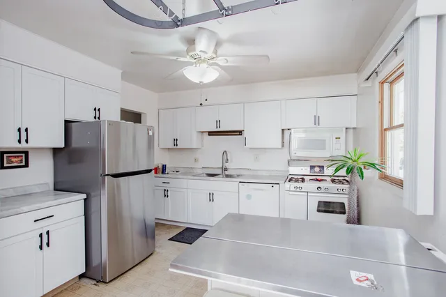 a kitchen with stainless steel appliances a refrigerator sink and white cabinets