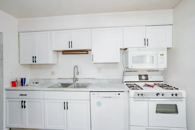 a kitchen with cabinets appliances a sink and a counter top space