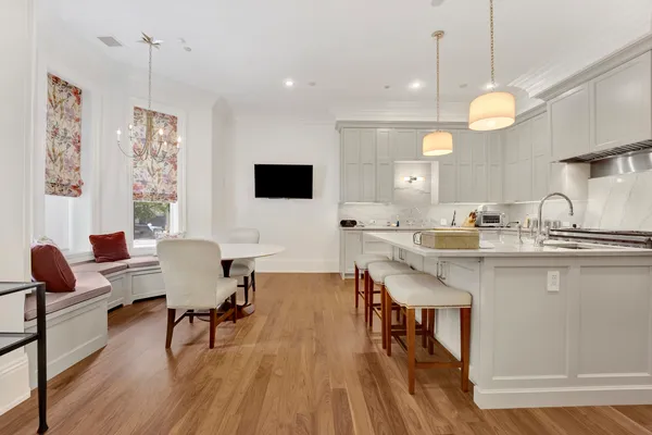 a kitchen with stainless steel appliances granite countertop a stove top oven a sink dishwasher a dining table and chairs with wooden floor