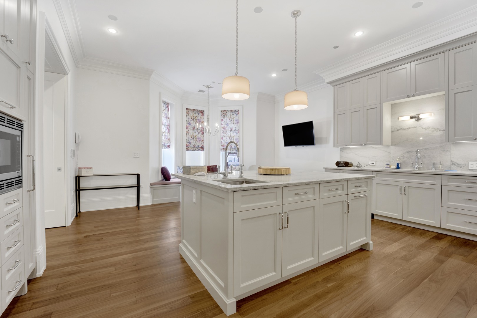 103 West Chestnut Street Chicago, IL 60610 - Photo 9 of 51 a large white kitchen with a white kitchen island and a wooden floor