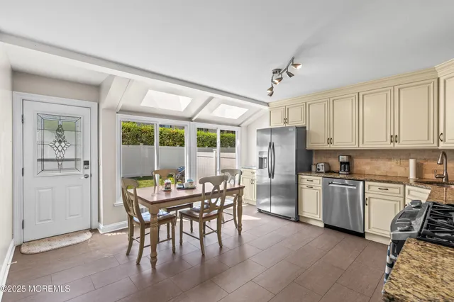 a kitchen with a dining table chairs and refrigerator
