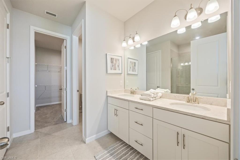 4687 Arboretum Circle, Unit 203 Naples, FL 34112 - Photo 18 of 24 a bathroom with a double vanity sink and a mirror