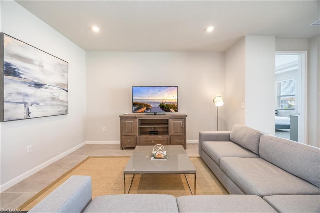 4687 Arboretum Circle, Unit 203 Naples, FL 34112 - Photo 6 of 24 a living room with furniture a flat screen tv and a fireplace