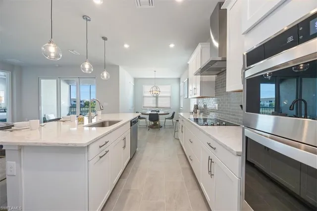 a large white kitchen with a large island oven a sink dishwasher and white cabinets with wooden floor