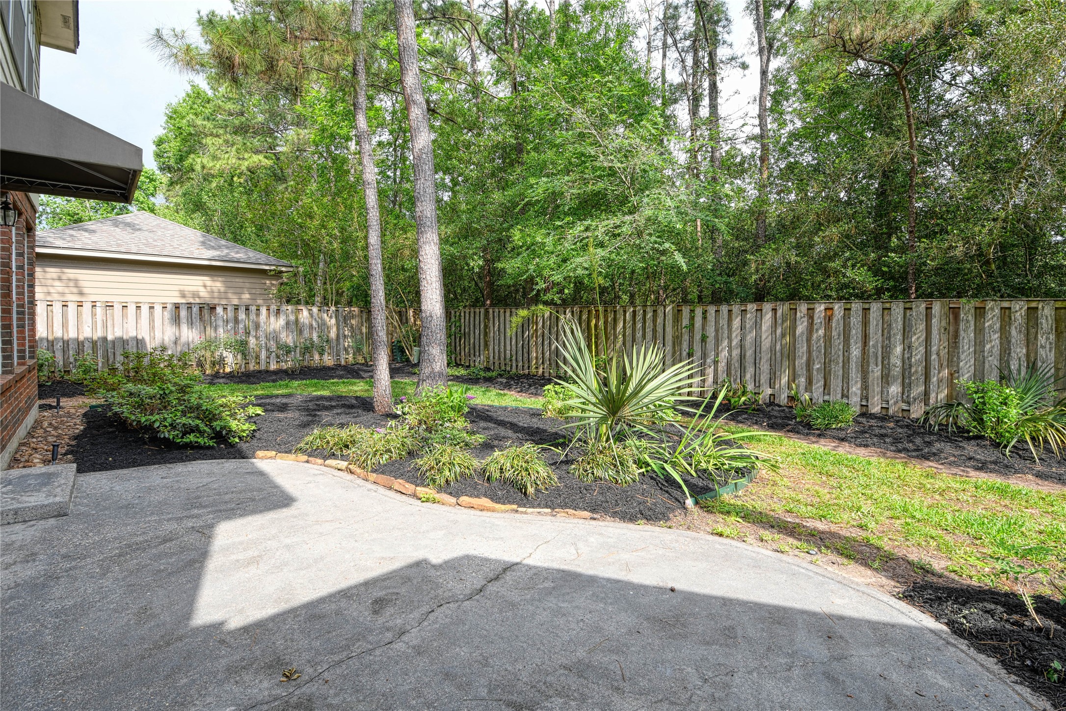 2 Woodmere Place Spring, TX 77381 - Photo 17 of 20 a view of a backyard with plants and large trees with wooden fence