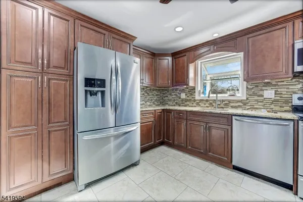 a kitchen with granite countertop stainless steel appliances a refrigerator and cabinets