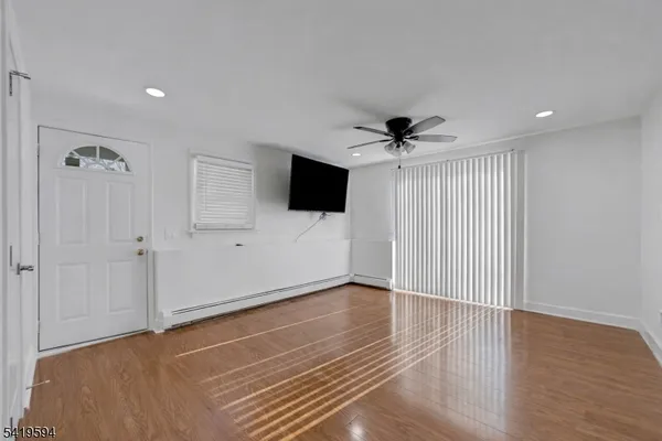 a view of an empty room with a ceiling fan and wooden floor