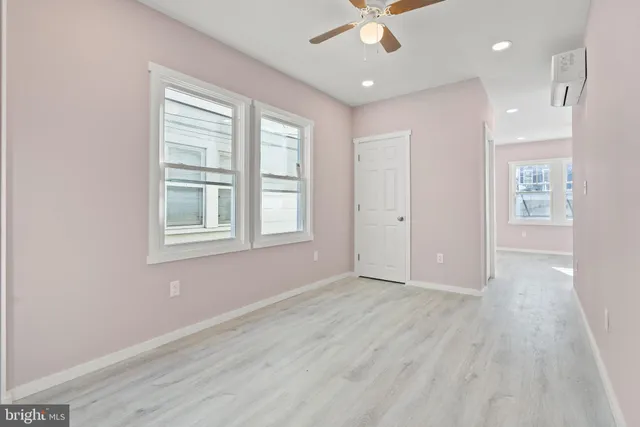 an empty room with wooden floor fan and windows