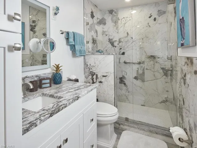 a bathroom with a granite countertop sink toilet and shower