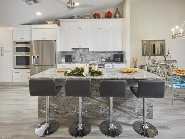 a kitchen with stainless steel appliances granite countertop a sink a stove a refrigerator and white cabinets