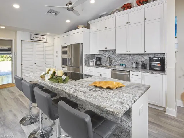 a kitchen with stainless steel appliances granite countertop a sink a stove and a wooden floors