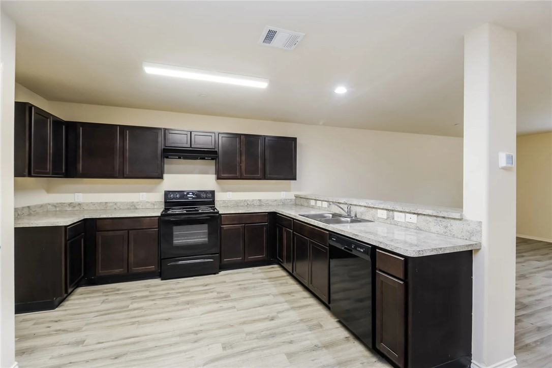a kitchen with stainless steel appliances granite countertop wooden cabinets a stove top oven a sink and dishwasher
