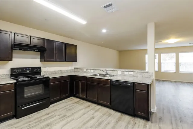 a kitchen with stainless steel appliances granite countertop a stove a sink and a microwave