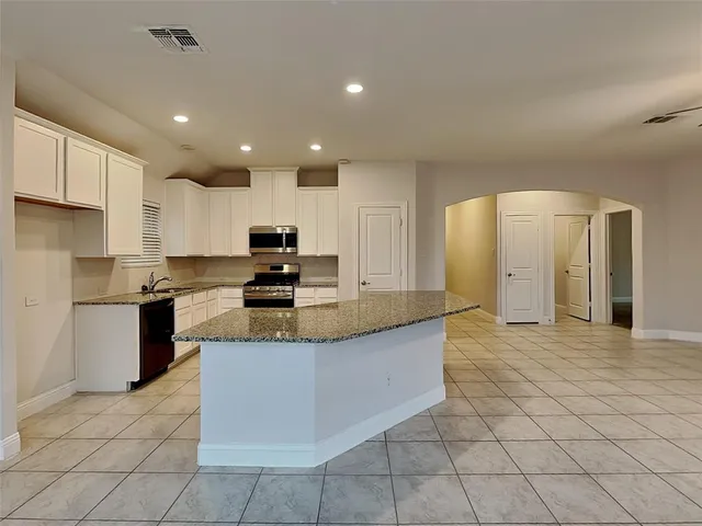 a large kitchen with stainless steel appliances granite countertop a stove top oven a sink and a refrigerator