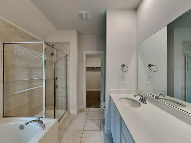 a bathroom with a tub sink vanity granite and shower