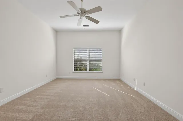 an empty room with a window and a fan