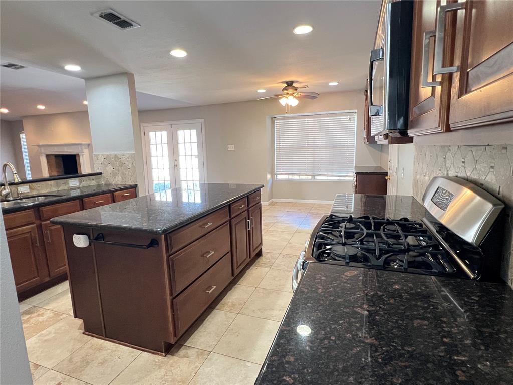 6151 Alpha Road Dallas, TX 75240 - Photo 13 of 39 a kitchen with kitchen island granite countertop a stove and a sink