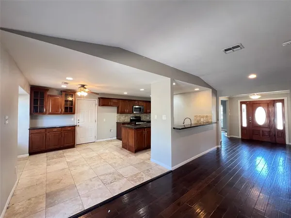 a kitchen with stainless steel appliances kitchen island granite countertop a stove a refrigerator a sink a oven with wooden floor and cabinets