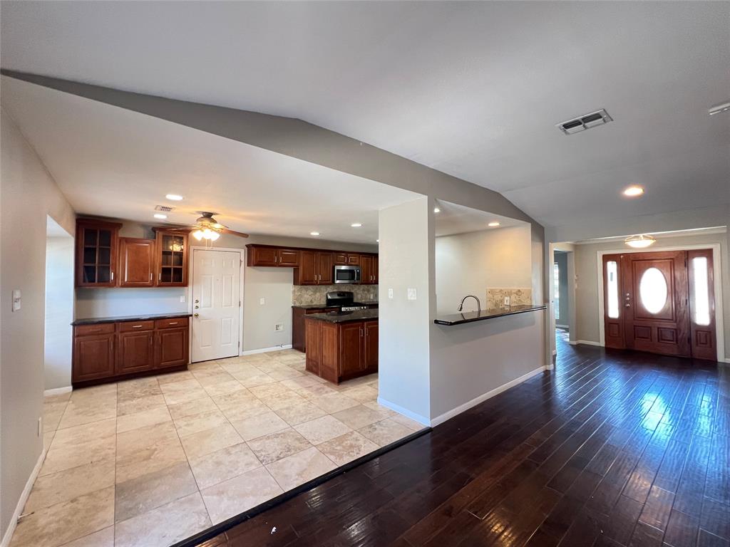 6151 Alpha Road Dallas, TX 75240 - Photo 3 of 39 a kitchen with stainless steel appliances kitchen island granite countertop a stove a refrigerator a sink a oven with wooden floor and cabinets
