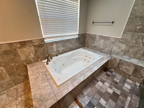 a bathroom with a tub a sink and glass door