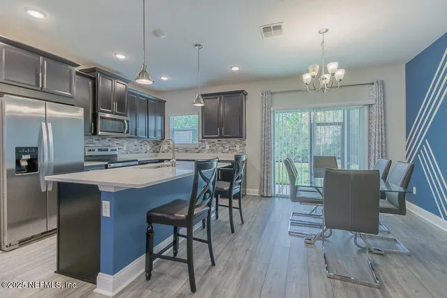 a kitchen with kitchen island stainless steel appliances a dining table chairs and wooden floor