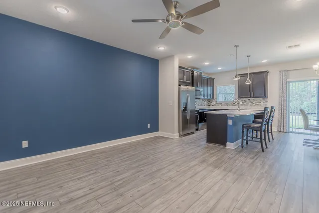 a view of kitchen with stainless steel appliances refrigerator microwave and dining table