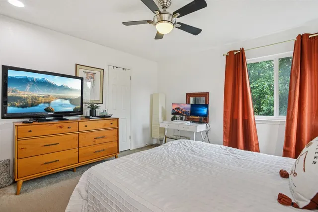 a bedroom with a bed a flat screen tv and a dresser