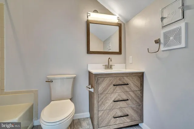 a bathroom with a toilet sink vanity and mirror