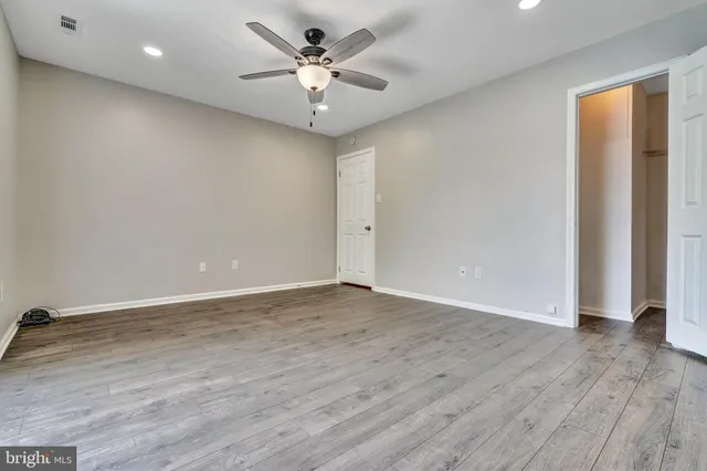 an empty room with wooden floor and ceiling fan