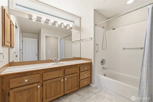 a spacious bathroom with a granite countertop sink a mirror a bathtub and shower