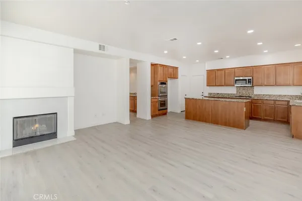 a view of kitchen with stainless steel appliances wooden floor and living room view