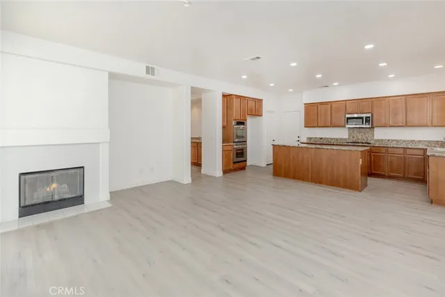a view of kitchen with stainless steel appliances wooden floor and living room view