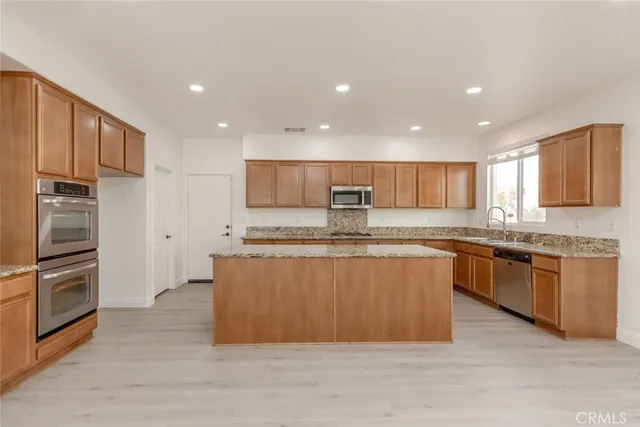 a large kitchen with stainless steel appliances granite countertop a large counter top a oven a refrigerator and a sink