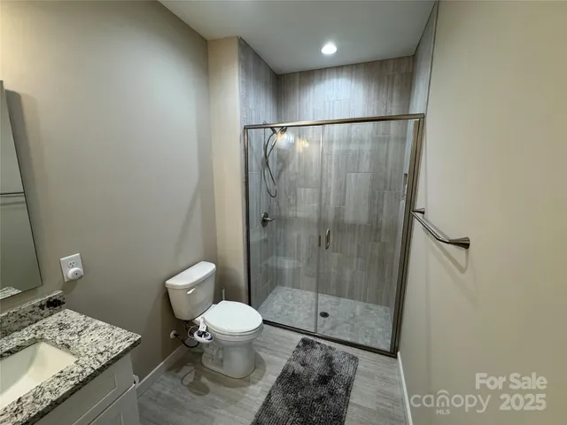 a bathroom with a granite countertop toilet a sink and shower