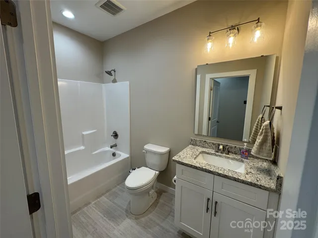 a bathroom with a granite countertop sink toilet a large mirror a bathtub and shower