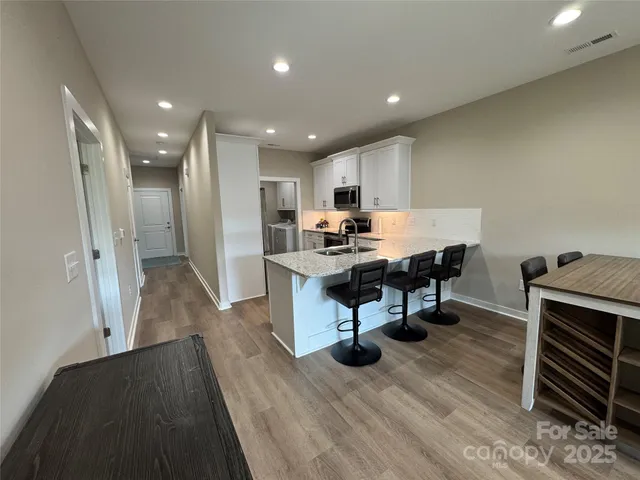 a living room with stainless steel appliances furniture a rug and a kitchen view